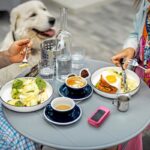 Pareja disfrutando de un desayuno al aire libre con un perro