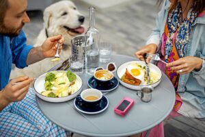 Pareja disfrutando de un desayuno al aire libre con un perro