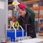 Técnico manipulando baterías en un entorno industrial con herramientas de seguridad