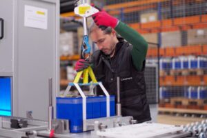 Técnico manipulando baterías en un entorno industrial con herramientas de seguridad