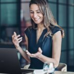 Mujer sonriendo mientras usa un laptop ASUS ExpertBook B3 G2 en una oficina moderna