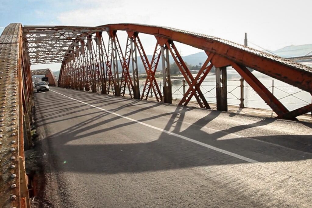 Puente metálico con estructura visible y carretera en uso