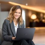 Mujer sonriente usando un portátil ASUS ExpertBook B3 G1 en un entorno moderno