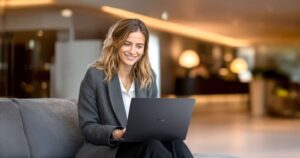 Mujer sonriente usando un portátil ASUS ExpertBook B3 G1 en un entorno moderno