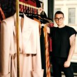 Christian Siriano posando junto a ropa en el Mystic Museum of Art