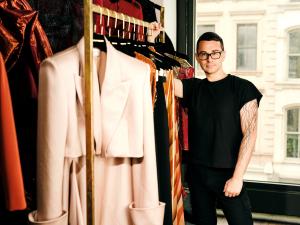 Christian Siriano posando junto a ropa en el Mystic Museum of Art