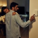 Padre con su hija en brazos activando alarma en casa