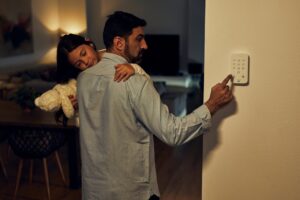 Padre con su hija en brazos activando alarma en casa